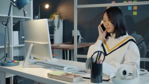 Vriendelijke Aziatische zakenvrouw spreken op mobiele telefoon bespreken van zaken werken in het kantoor in de avond — Stockvideo