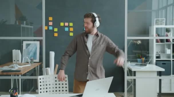 Безтурботний бізнесмен розважається на роботі, танцюючи в навушниках один — стокове відео