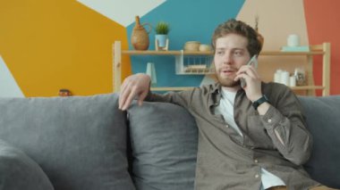 Dairesinde cep telefonuyla sohbet eden genç adam dairede sohbetin tadını çıkarıyor.