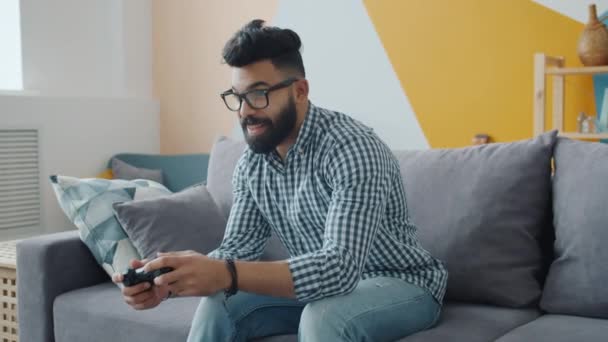 Zwolniony ruch arabski facet gra w gry wideo zabawy w nowoczesnym mieszkaniu — Wideo stockowe