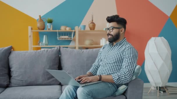 Przystojny Arab człowiek freelancer za pomocą laptopa działa z mieszkania sam — Wideo stockowe