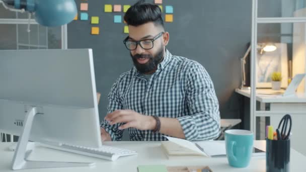 Homme souriant métis portant des lunettes de travail avec ordinateur sur le lieu de travail — Video