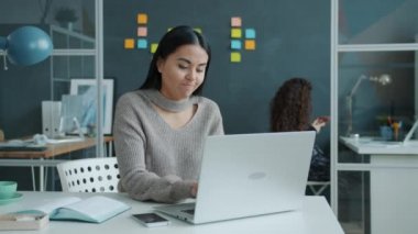 Asyalı sinirli bir çalışan dizüstü bilgisayar kullanıyor. Sonra kızgın ve mutsuz bir şekilde işyerinden ayrılıyor.