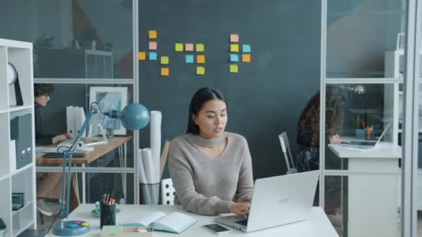 현대 직장에서 노트북을 가지고 일하는 아시아 소녀가 두 통을 느끼다 — 비디오