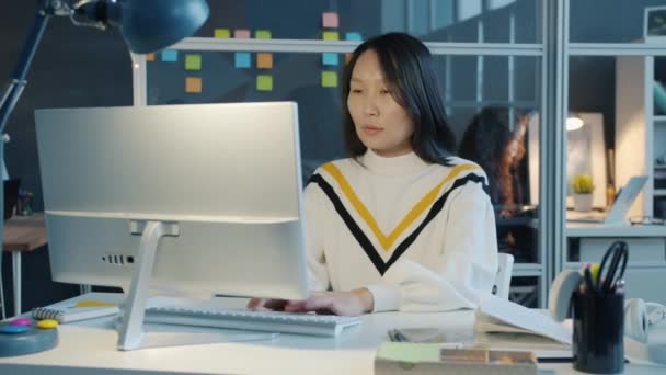 Unavená asijská žena pracující s počítačem pak masírovat hlavu pocit vyčerpaný v kanceláři ve večerních hodinách — Stock video