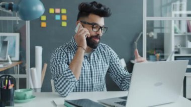 Ofiste cep telefonuyla konuşan Orta Doğulu genç adam yavaş hareket ediyor.