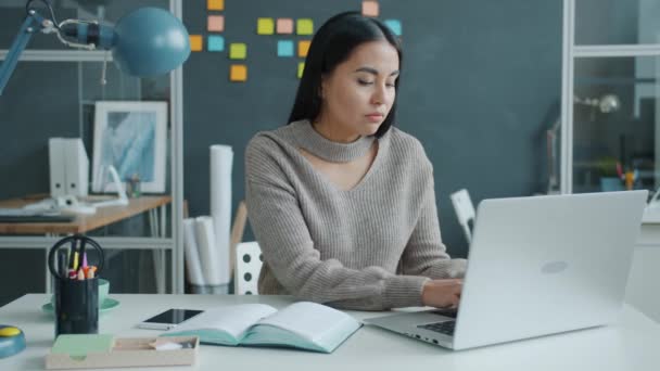 Slow motion van mooi aziatisch meisje met behulp van laptop dan het maken van notities op het werk — Stockvideo