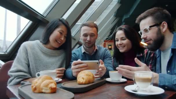 Fröhlicher Typ, der Fotos von Speisen und Getränken macht und Fotos mit Freunden teilt, die lachen — Stockvideo