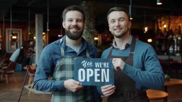 Porträt von Männern Geschäftspartner halten wir sind offen Schild stehen in modernen Café — Stockvideo