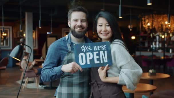 Портрет повільного руху чоловіка і жінки, що тримає відкритий знак в сучасному ресторані — стокове відео