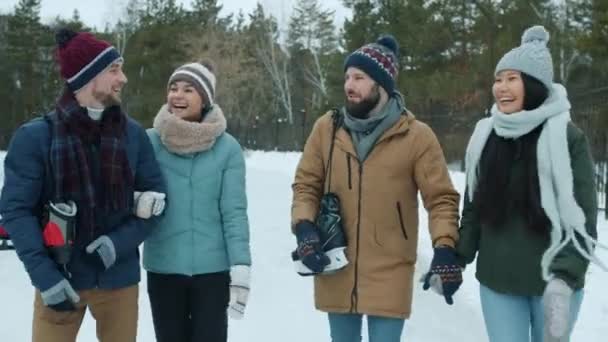 Vidám barátok lányok és fiúk sétálnak a parkban együtt korcsolyázók élvezi a természetet — Stock videók