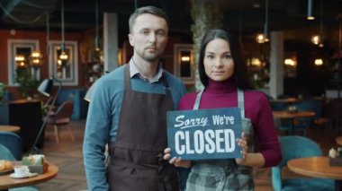 Mutlu çift tabelayı değiştirip güzel bir kafenin içinde duruyor.