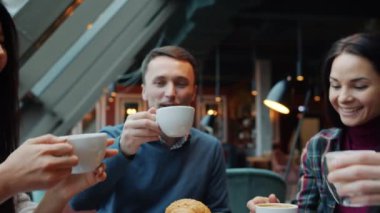 Kahve fincanlarında kutlama yapan erkek ve kadınların yavaş çekimde kahkahalarla gülmeleri.