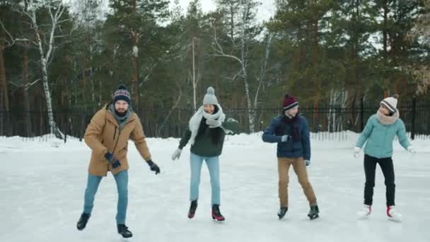 Jovens felizes patinando no gelo e dançando se divertindo rindo no parque de inverno — Vídeo de Stock