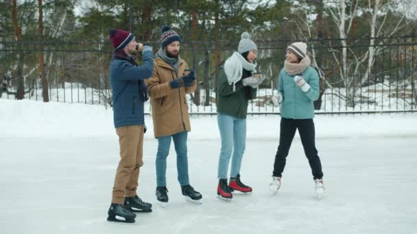 Pessoas felizes amigos bebendo tomar café no ringue de patinação no gelo ao ar livre falando rindo — Vídeo de Stock