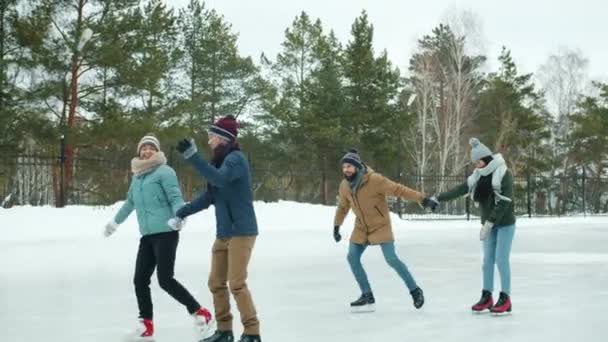 Jovens casais patinando na pista de gelo no parque de inverno conversando desfrutando de data ao ar livre — Vídeo de Stock