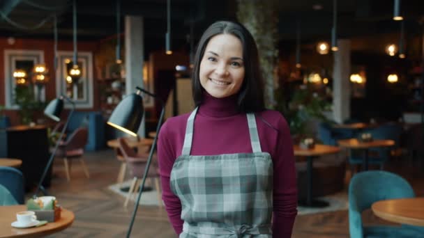 Slow motion av glad servitris visar ja vi är öppen skylt stående i ny restaurang leende — Stockvideo