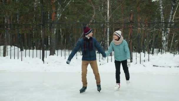 Movimento lento de homem e mulher felizes se divertindo com patinação no gelo no parque de inverno — Vídeo de Stock