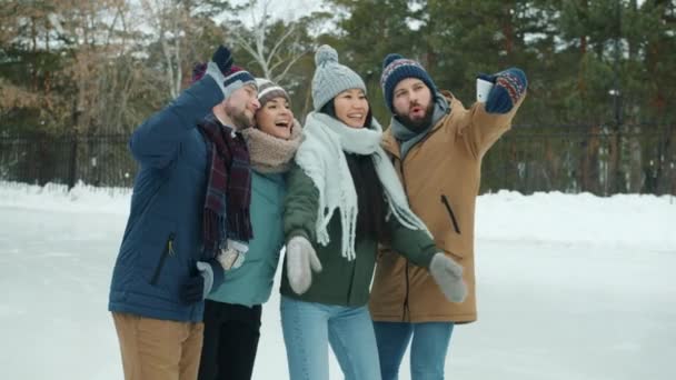 Amigos engraçados tirando selfie com smartphone posando em pé na pista de patinação no gelo — Vídeo de Stock