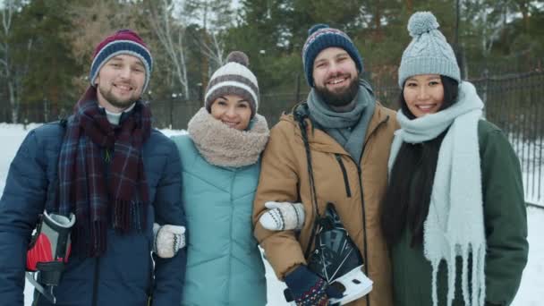 Portrait of happy friends men and women holding ice-skates standing in park in winter smiling — Stock Video