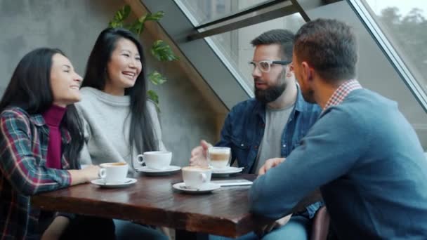 Alegre amigos masculinos y femeninos charlando riendo y haciendo high-five en acogedora cafetería — Vídeo de stock