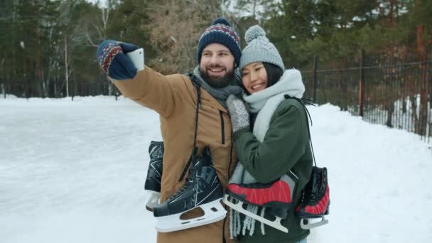 Bella giovane coppia che prende selfie con smartphone all'aperto nel parco con pattini da ghiaccio — Video Stock