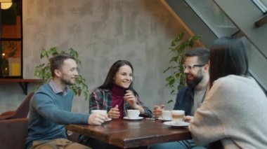 Genç adam arkadaşlarıyla sohbet ediyor. Sonra da akıllı telefonla ödeme yapıyor. Cafe 'de garsonla konuşuyor.