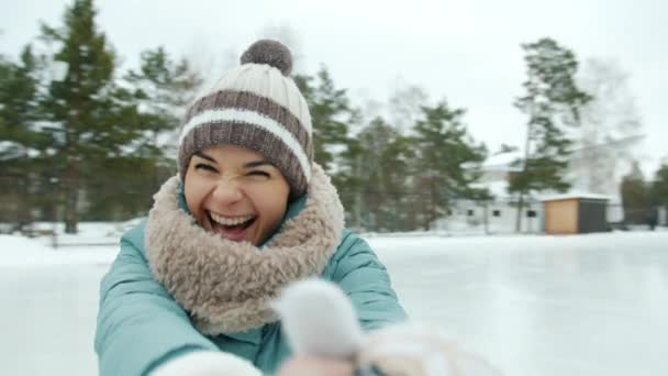 Portrait of happy young woman in warm clothes ice-skating laughing looking at camera — Stok Video