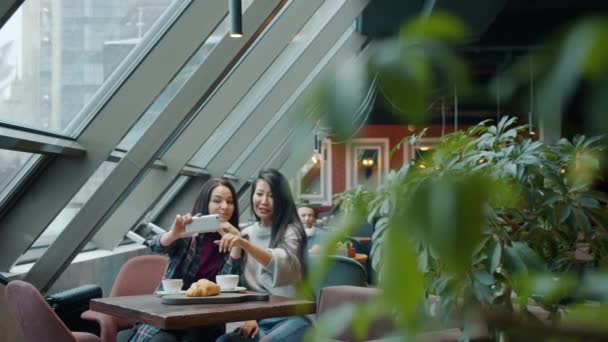 Powolny ruch pięknych kobiet robiących selfie przy stole w kawiarni pozujących śmiejąc się dobrze — Wideo stockowe