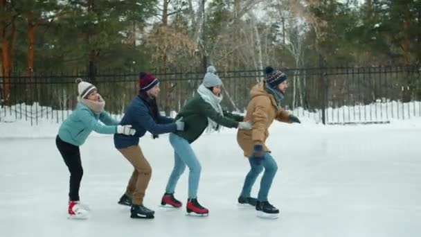 Långsamma rörelser av lekfulla män och kvinnor som har kul skridskoåkning och skrattar i parken — Stockvideo