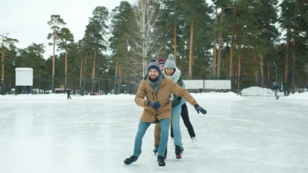 Gadis muda yang bahagia dan pria berseluncur es di danau beku di taman bersenang-senang tertawa — Stok Video