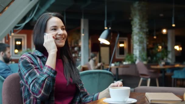 Nettes Mädchen, das in der Mittagspause auf dem Handy sitzt und lächelt. — Stockvideo