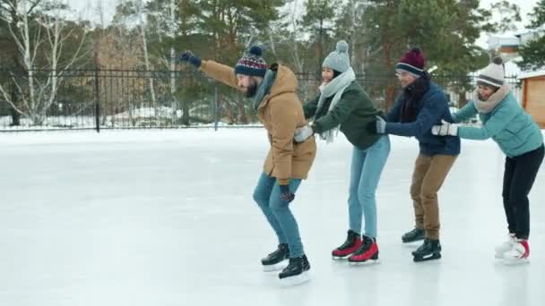 Movimento lento de jovens alegres patinação no gelo no parque juntos rindo se divertindo — Vídeo de Stock