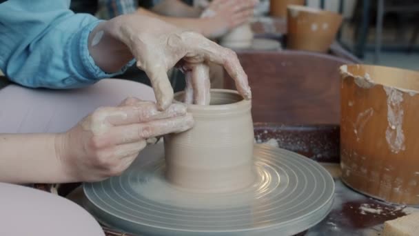 Primer plano de las manos de arcilla de moldeo masculino y femenino en la rueda de cerámica en el taller — Vídeos de Stock