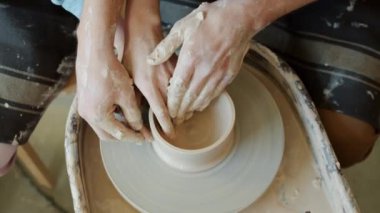 Kadın ve erkeğin elleri yavaş hareket ediyor. Tekerlek üzerinde esrar yapıyorlar.