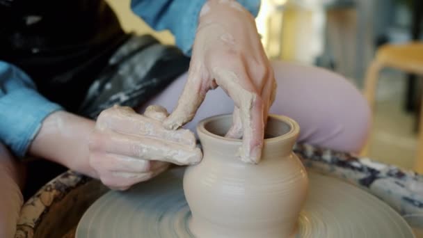Close-up of female hands working with wet clay on potters wheel shaping bowl — Stock Video