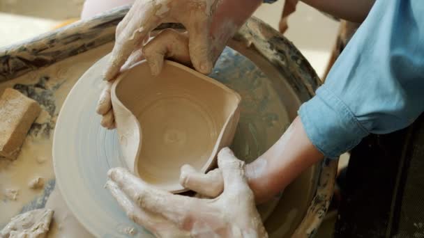 Top view of male and female hands making heart shape bowl in pottery studio — Stock Video
