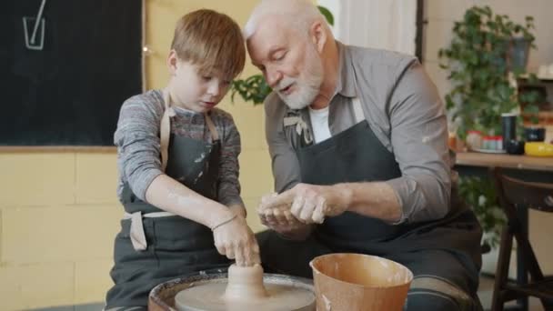 Kvalifikovaný chlapec tvarování váza v házení kola práci s pečující dědeček — Stock video