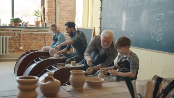 Vreugdevolle mensen volwassenen en kind praten en glimlachen tijdens pottenbakken in workshop — Stockvideo