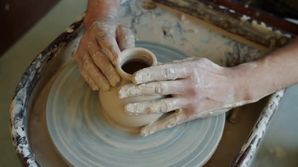 Close-up of guys hands molding ceramic vase working with potters wheel in studio — Stock Video