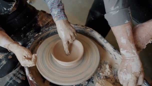 Close-up of adult and childs hands making ceramic bowl from clay on pottery wheel — Stock Video