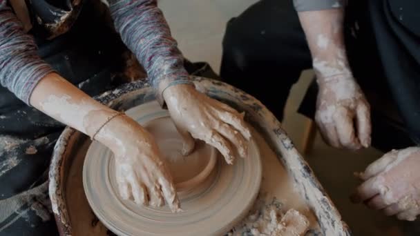 大人の監督の下で回転ホイールで作業粘土からボウルを作る男の子の手 — ストック動画