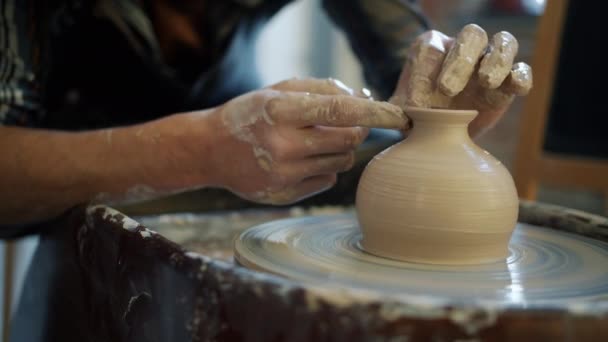 Close-up van pottenbakkers handen bedekt met klei maken mooie vaas op gooien wiel — Stockvideo