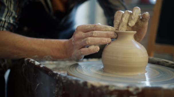 Close-up of ceramic vase spinning on potters wheel and male hands shaping clay — Stock Video