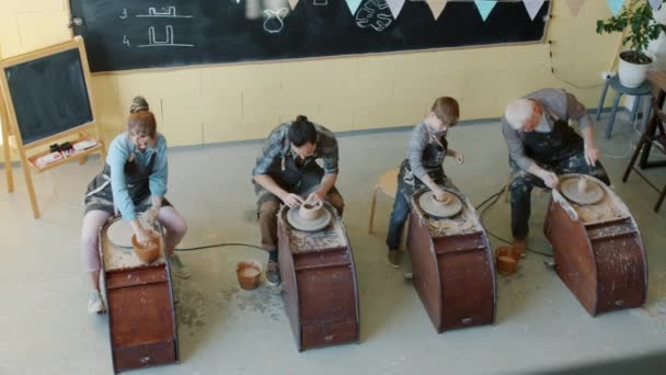 Sudut pandang yang tinggi dari orang-orang wanita dan anak-anak melakukan tembikar pada melemparkan roda di bengkel — Stok Video