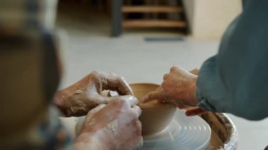 Kız ve erkek eller, stüdyoda tekerlerin üzerinde esrar yapmak için kil kalıbı çıkarıyorlar.