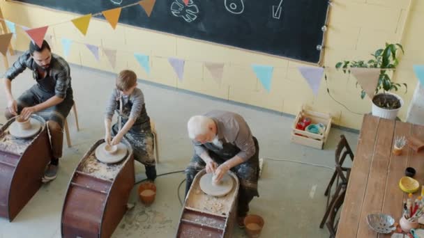 Hoge hoek zicht van diverse groep mensen volwassenen en kind bezig met aardewerk in werkplaats — Stockvideo
