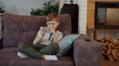 Akıllı telefonlu mutlu çocuk video oyunu oynuyor. Evde eğleniyor.