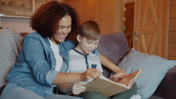 Joyeux Afro-Américain fille babysitter lecture drôle histoire à heureux enfant à l'intérieur — Video