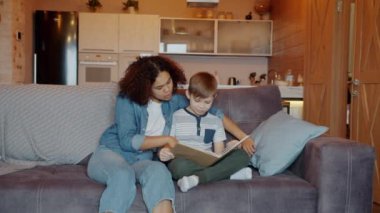 Dost canlısı Afrikalı Amerikalı dadı stüdyo dairesindeki zeki çocuğa masal okuyor.